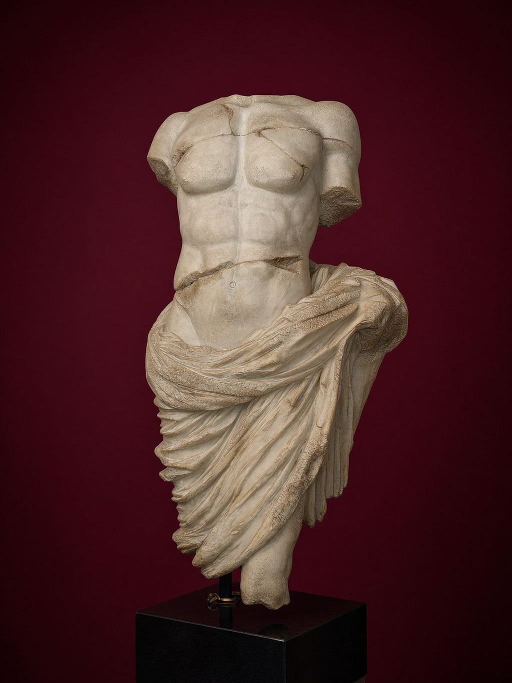 Classical draped male torso sculpture in aged white marble finish mounted on matte black square pedestal